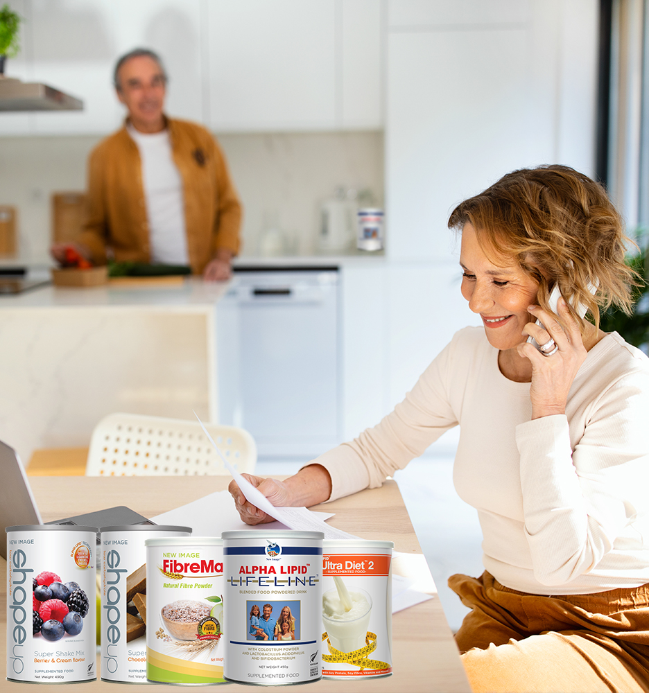 Happy senior woman talking on smartphone and checking bills when husband preparing dinner at kitchen, selective focus on smiling wife. Solving vacation issues. Utility bills documents